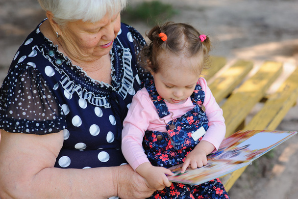 Grand-mère et petite-fille lisant le livre dans le parc
 - Photo, image