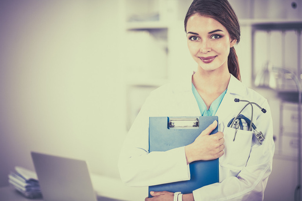 Smiling female doctor with a folder in uniform standing at hospital - Φωτογραφία, εικόνα