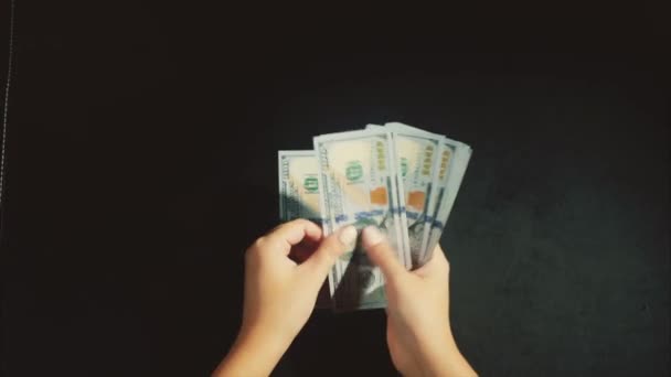 Las manos de la mujer cuentan un paquete de dólares en el fondo negro
 - Metraje, vídeo