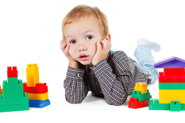 kleiner Junge spielt mit Spielzeug und baut Haus isoliert auf weiß - Foto, Bild