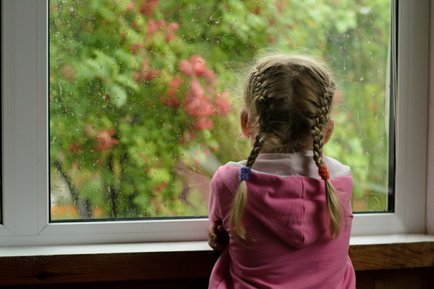 chica con coletas viendo la lluvia fuera de la ventana
 - Foto, Imagen