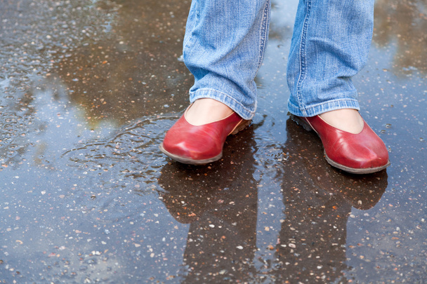 秋の雨の水たまりで赤い靴に足 - 写真・画像