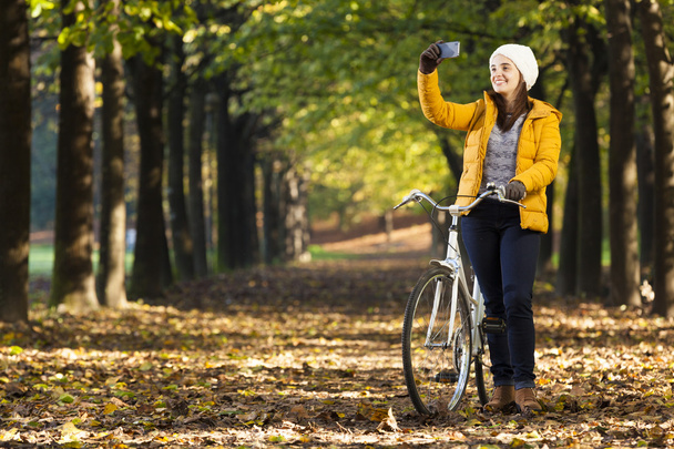 girl on bike taking photos with cell phone outdoors - Photo, Image