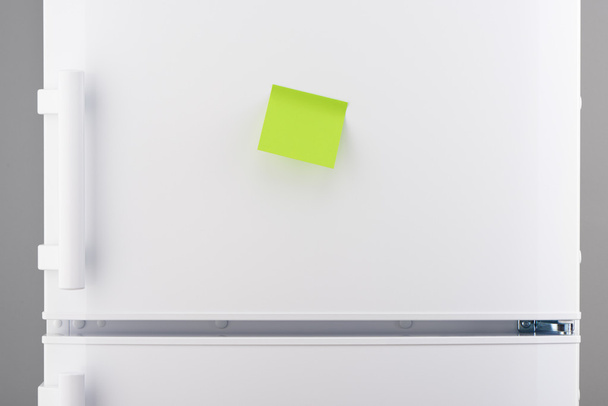 Blank green sticky paper note on white refrigerator  - Фото, изображение