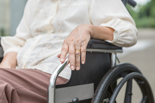 Elderly hands on a wheelchair. - Foto, Imagen