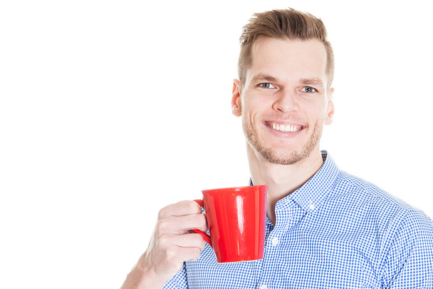 Guapo sonriente hombre de negocios sosteniendo taza roja aislado sobre fondo blanco
 - Foto, Imagen