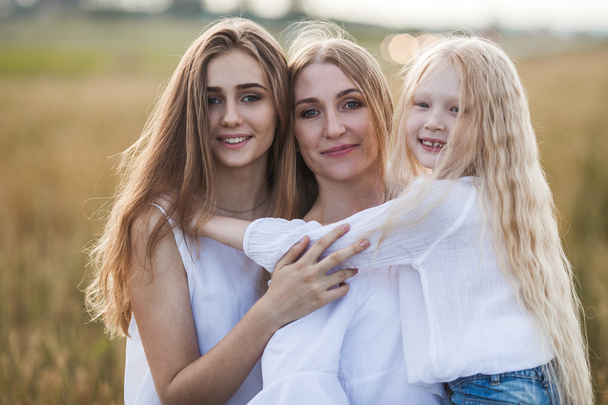 beautiful young mother and her daughters at the wheat field - Photo, image