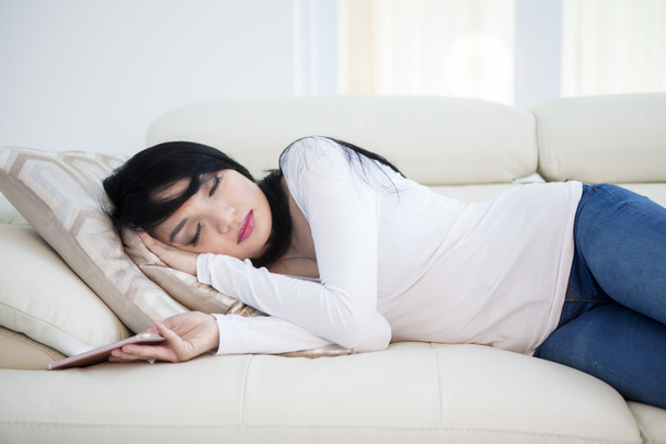 Woman with cellphone sleeps on sofa - Fotó, kép