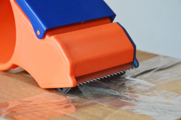 rozprašovačem páskové těsnění hnědou krabičku na odesílání - Fotografie, Obrázek