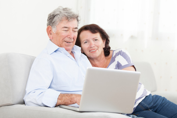 Senior couple laughing while using laptop - Fotografie, Obrázek