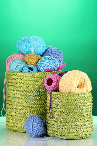 Colorful yarn for knitting in green basket on green background - Фото, изображение