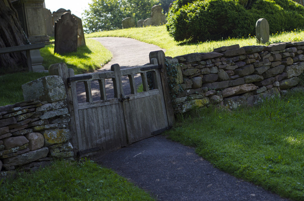 Velho portão duplo de madeira na parede de pedra seca para o cemitério
 - Foto, Imagem