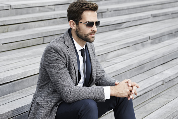 Businessman in sunglasses sitting on staircase - Zdjęcie, obraz