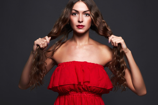 beauty woman with long curly hair.Beautiful elegant lady in red dress - 写真・画像