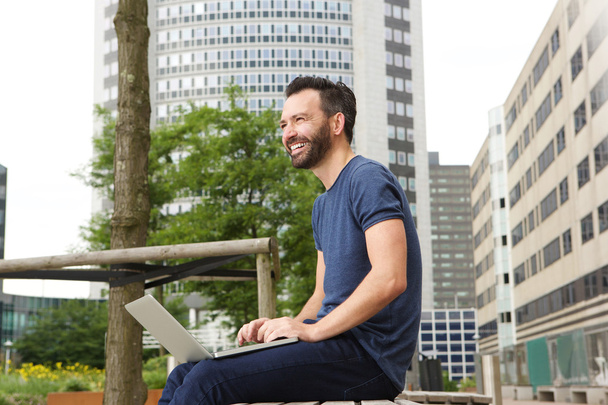 Gelukkig midden leeftijd man buiten zitten met laptop - Foto, afbeelding