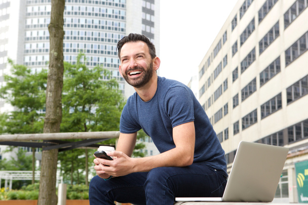 fröhlicher Mann sitzt auf Bank im Freien - Foto, Bild