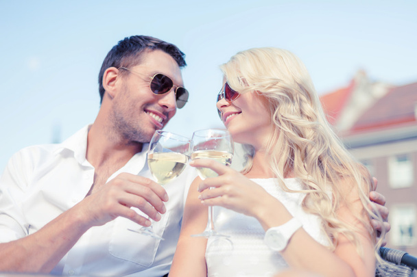 smiling couple in sunglasses drinking wine in cafe - Valokuva, kuva