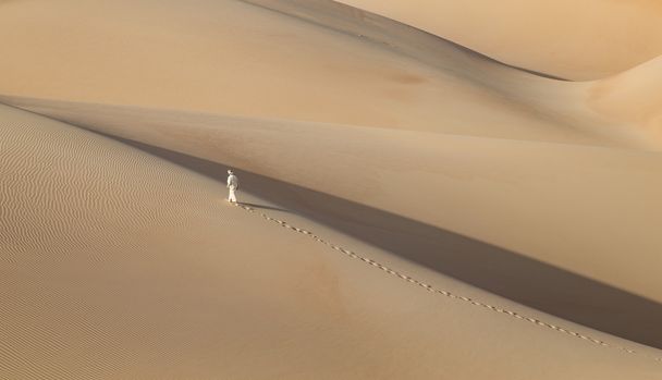 Homem em kandura num deserto ao nascer do sol
 - Foto, Imagem