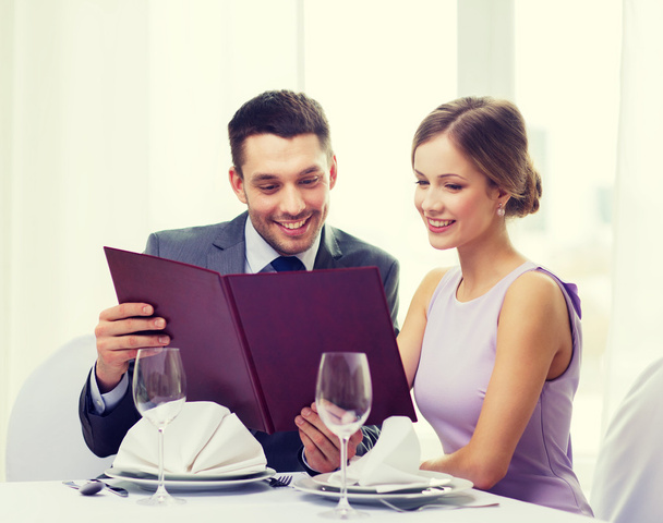 smiling couple with menu at restaurant - Foto, Imagen