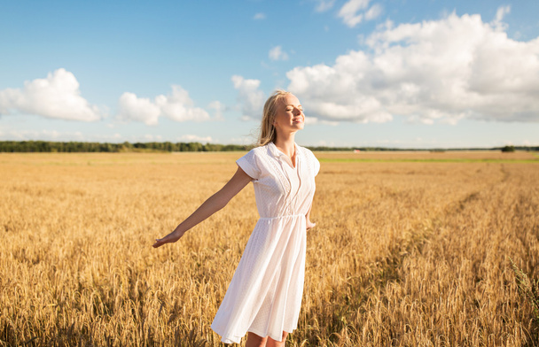 smiling young woman in white dress on cereal field - Photo, image