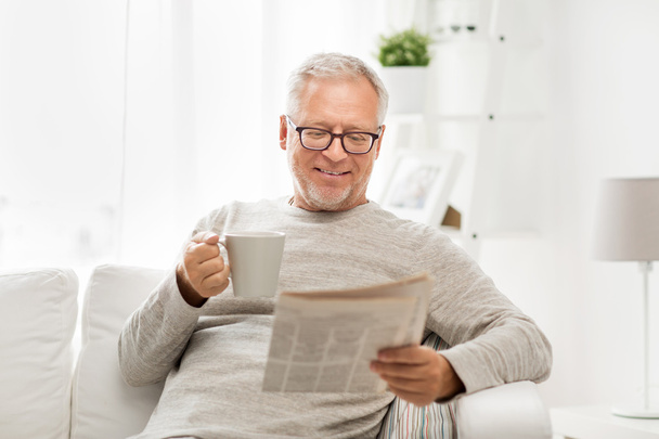senior man in glasses reading newspaper at home - Foto, immagini