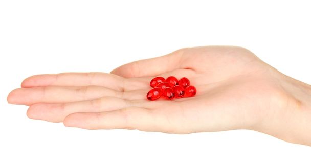 Woman's hand holding a red pill on white background close-up - Zdjęcie, obraz