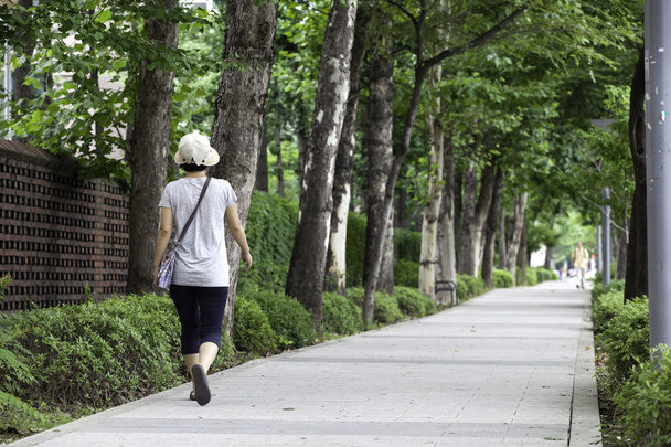 Woman walks along sidewalk. - Photo, Image
