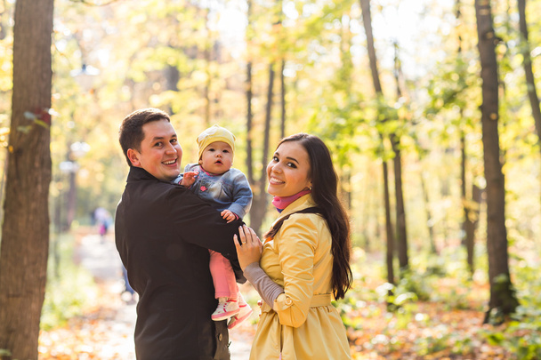 любовь, родительство, семья, сезон и люди концепция - улыбающаяся пара с ребенком в осеннем парке
 - Фото, изображение