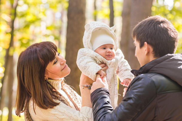 love, parenthood, family, season and people concept - smiling couple with baby in autumn park - Photo, Image