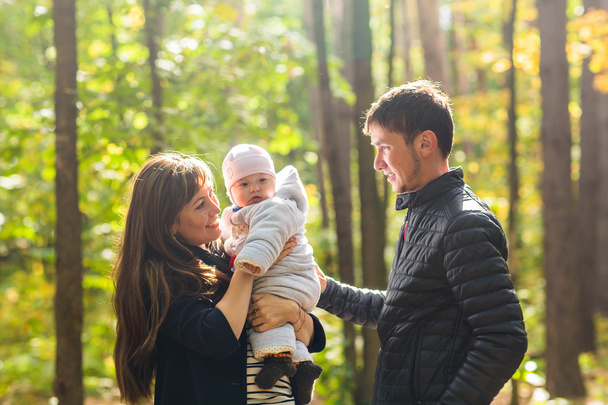 любовь, родительство, семья, сезон и люди концепция - улыбающаяся пара с ребенком в осеннем парке
 - Фото, изображение
