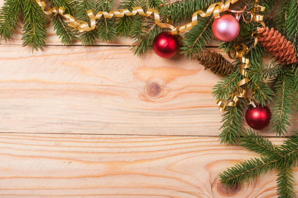 Eckrahmen aus Tannenzweigen mit Weihnachtsdekoration auf hellem Holzgrund - Foto, Bild