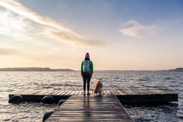 Femme avec chien profiter du lever du soleil au lac, randonneur
 - Photo, image
