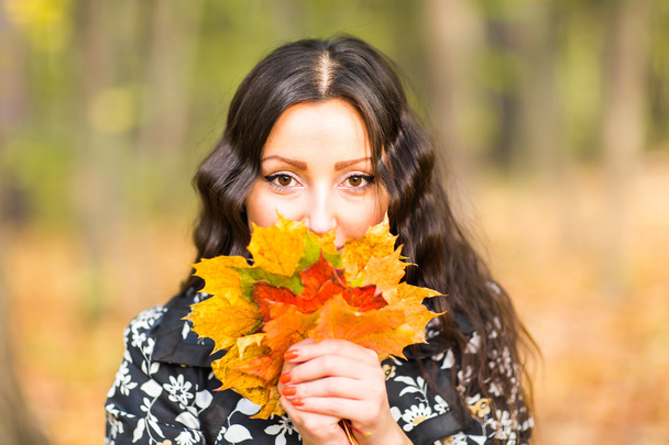 Mujer joven con hojas de otoño en la mano y caída de arce amarillo fondo del jardín - Foto, Imagen
