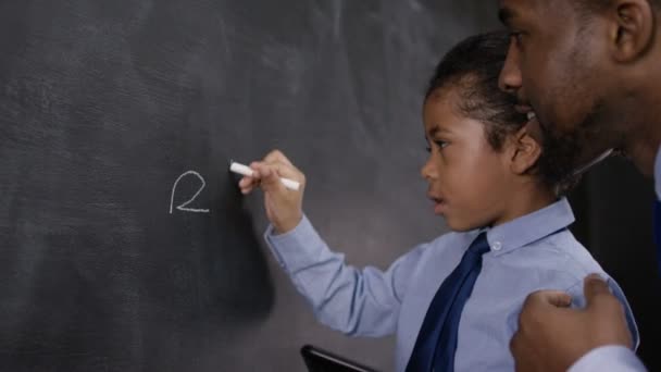 Man and boy writing on blackboard - Πλάνα, βίντεο