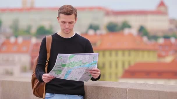 Homem turista com um mapa da cidade e mochila na Europa. Garoto caucasiano olhando com mapa da cidade europeia em busca de atrações
. - Filmagem, Vídeo