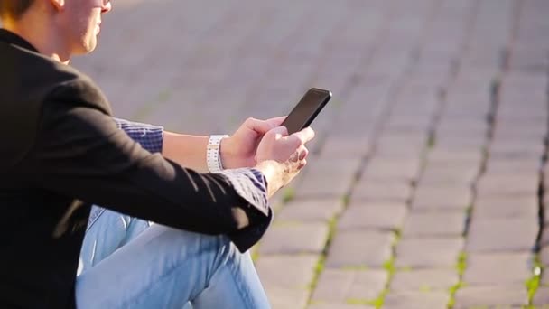 Zbliżenie męskich rąk trzyma komórkę na zewnątrz na ulicy. Mężczyzna korzystający ze smartfona. - Materiał filmowy, wideo