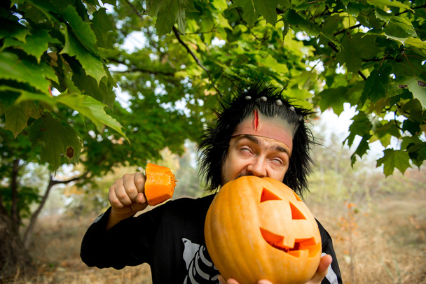 Un hombre terrible. Zombis humanos sosteniendo una calabaza en sus manos. Símbolo de la fiesta de Halloween
. - Foto, imagen