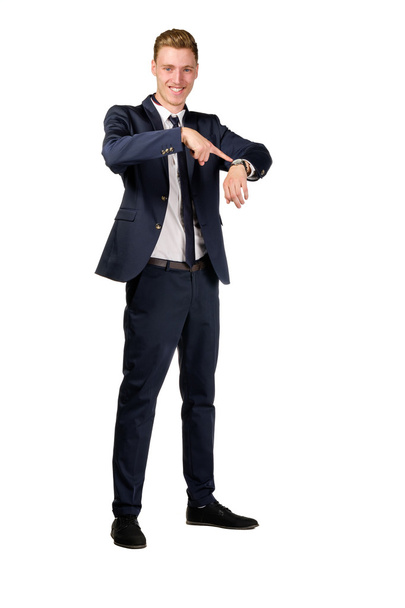 Молодой бизнесмен в костюме указывает на часы
 - Фото, изображение