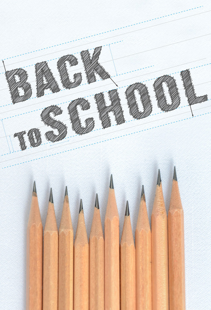 Paper with inscription word BACK TO SCHOOL near wooden pencil with copy space - Foto, imagen