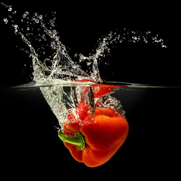 Red bell pepper falling in water with splash on black background - Foto, immagini