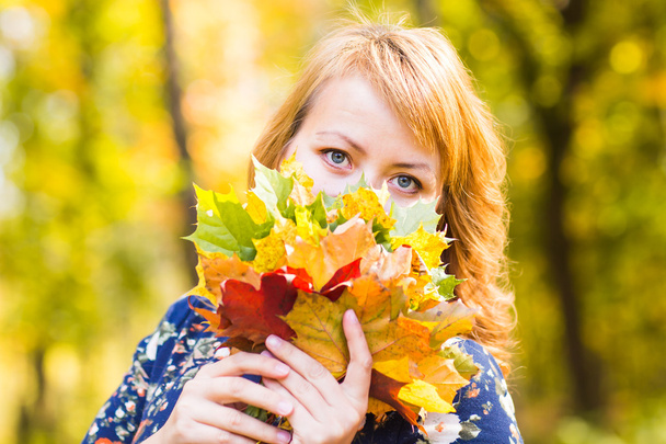 Γκρο πλαν, νεαρή γυναίκα με το σφενδάμνου φθινόπωρο φύλλα - Φωτογραφία, εικόνα