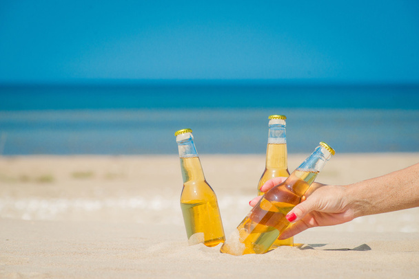 Botellas de cerveza heladas en la arena bajo el sol
 - Foto, Imagen