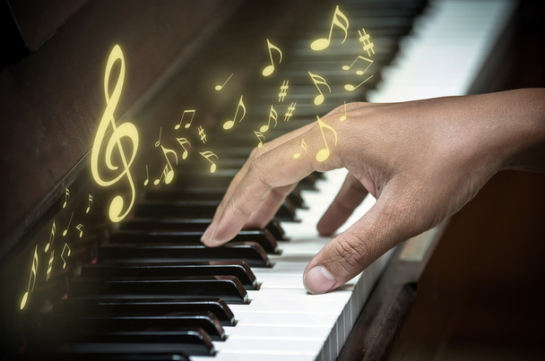 Mão tocando piano com notas de música
 - Foto, Imagem