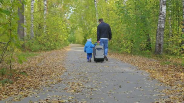 Hombre y niño con una maleta caminando por un sendero forestal
 - Imágenes, Vídeo