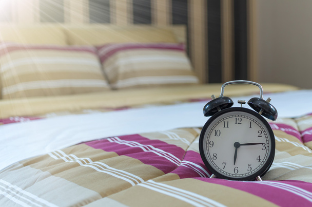 Reloj despertador retro en la cama
  - Foto, imagen