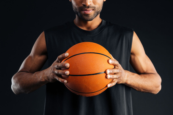 Cropped image of a concentrated african basketball player holding ball - Фото, зображення