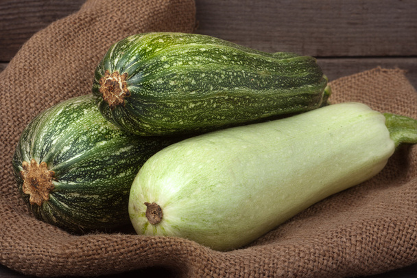 green zucchini and courgette on sackcloth wooden background - Photo, Image