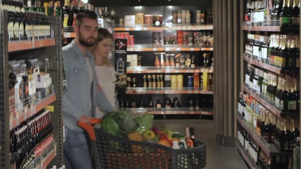 Couple choose alcohol at the hypermarket - Footage, Video