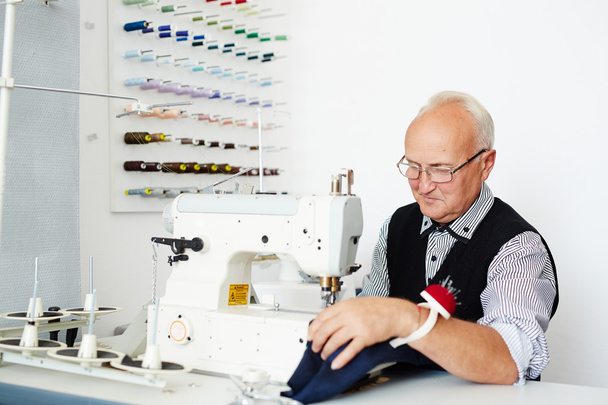 Mature tailor sewing clothes in workshop  - Photo, Image