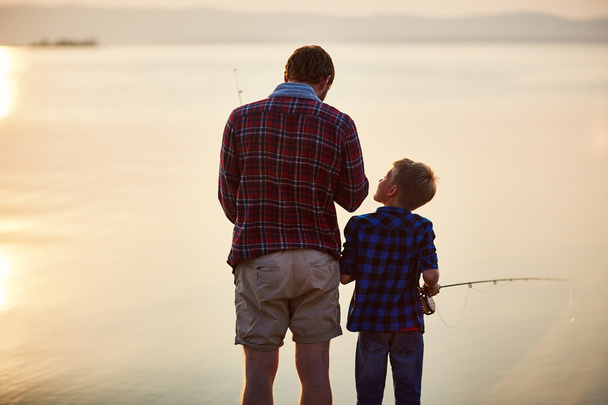 Little boy and his father fishing at sunset  - 写真・画像